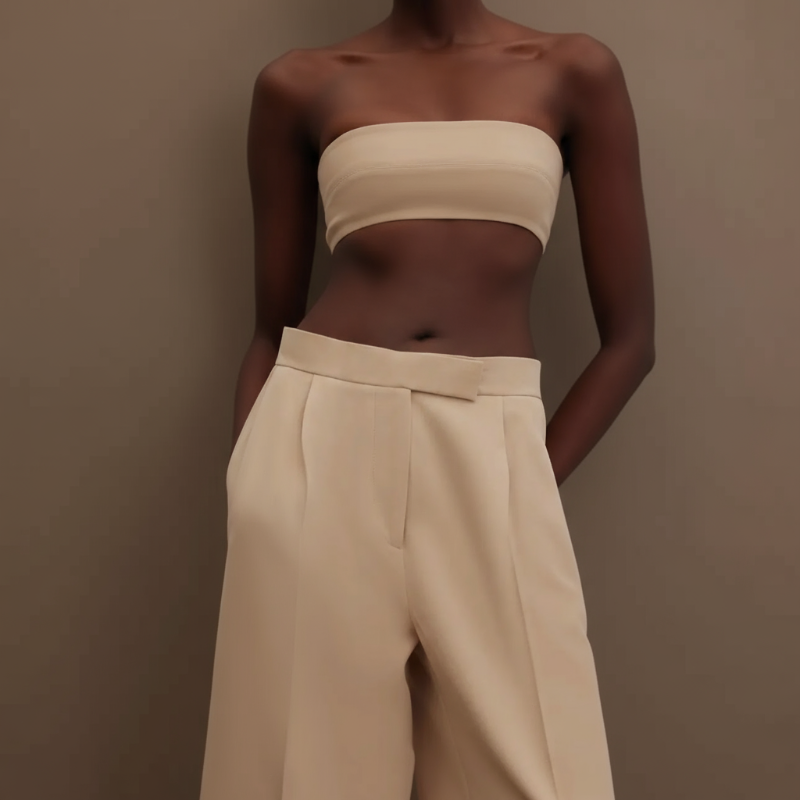 Woman wearing a beige strapless top and high-waisted suit pants