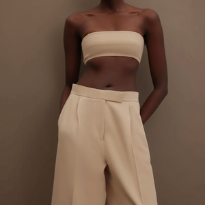 Woman wearing a beige strapless top and high-waisted suit pants
