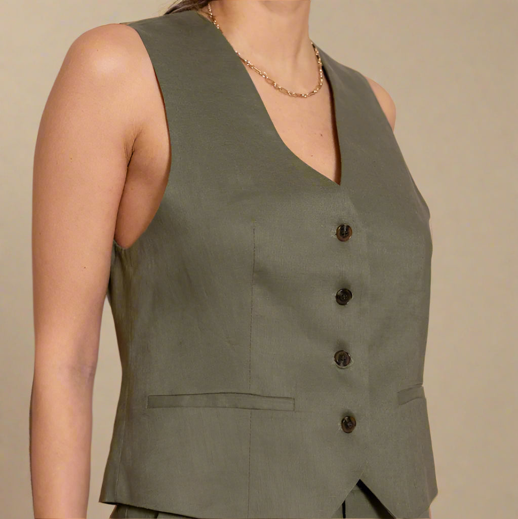 Green linen vest with buttons on a plain background