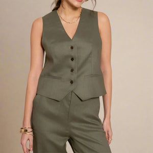 Woman wearing a green linen vest and pants against a beige background