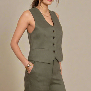Woman wearing a green linen vest and pants set against a beige background