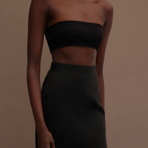 Woman wearing a black strapless top and skirt against a neutral background